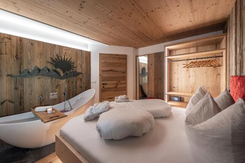 a bedroom with a large bed and a bath tub at Oberkantiolhof in Villnoss