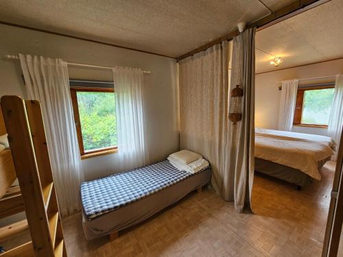 a small bedroom with a bed and two windows at Sandmo Holiday Home 11 in Eckerö