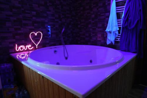 a pink bath tub with a love sign on it at SpaOk & Play in Mărgăriţi