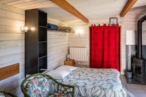 a bedroom with a bed and a red curtain at chalet 2 personnes in Mialanes