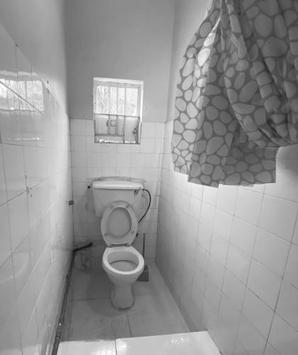 a small bathroom with a toilet and a window at Homestay in Wilkinson road in Freetown