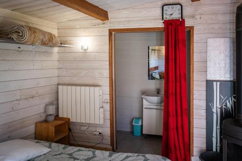 a bedroom with a red curtain and a sink at chalet 2 personnes in Mialanes