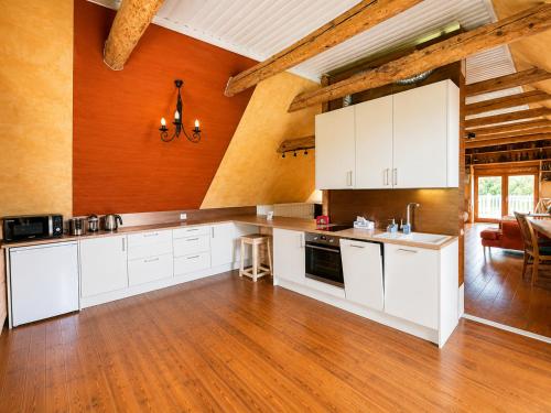 a kitchen with white cabinets and a wooden floor at Kalvi tee Puhkemaja in Viru-Nigula
