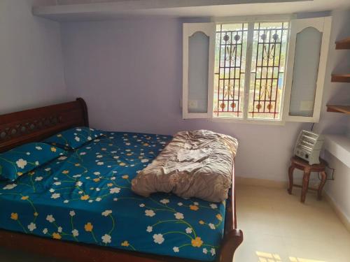 a bedroom with a bed with a blue comforter and a window at SM GARDENS Nature Stay Kodaikanal in Oothu