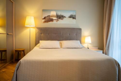 a bedroom with a large white bed with two pillows at Naglio apartamentai Elija in Šventoji