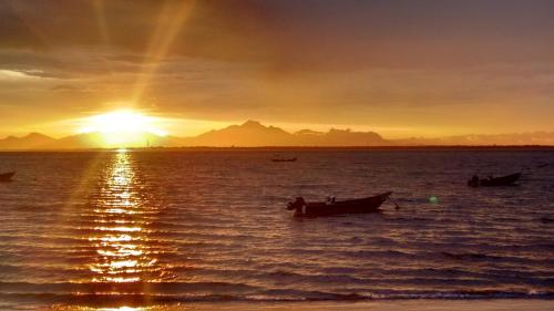 a sunset with two boats in the water at Pousada Estrela do Mar in Ilha do Mel