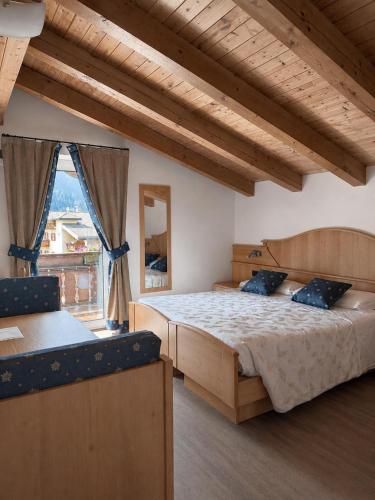 ein Schlafzimmer mit einem großen Bett und einem großen Fenster in der Unterkunft Hotel Ai Pini in Vigo di Fassa