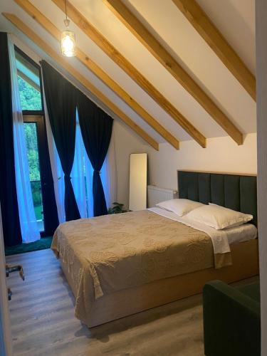 a bedroom with a large bed with blue curtains at MTA house - Borjomi in Borjomi