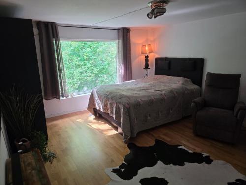 a bedroom with a bed and a window and a chair at Mysigt hus på 40 kvm i Målaskog in Ryssby