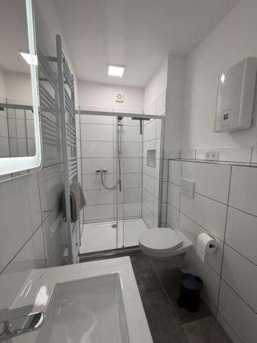 a white bathroom with a shower and a toilet at Urban Nest Burg - Design Apartment mit Smart-TV, Self Check-in & Free Parking in Burg