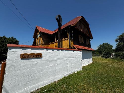 a building on top of a white wall with a house at Čardak Mraclin in Mraclin