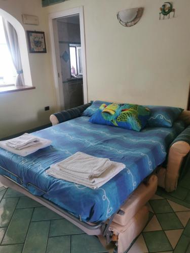 a bed in a living room with a blue blanket at Monolocale Ischia Isola Verde in Ischia Town