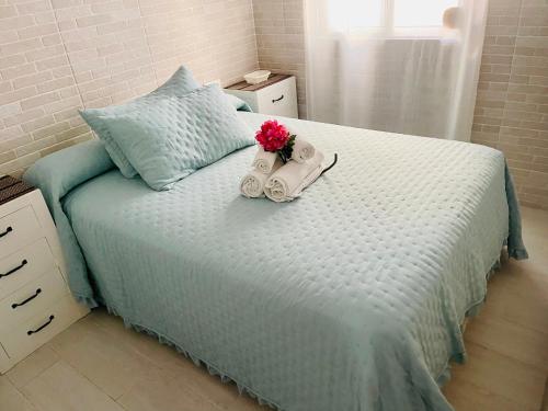 a bed with a bouquet of flowers and a alarm clock at AITA CASA BARBATE in Barbate