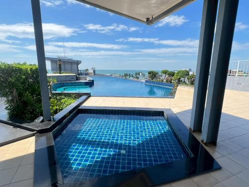 a swimming pool with a view of the ocean at The Patio Bangsaen Cozy Condo in Chon Buri