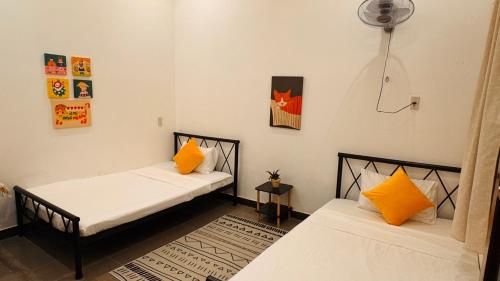 two beds in a room with yellow pillows at Ni Nớ Home in Hue