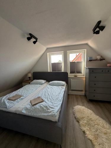 ein Schlafzimmer mit einem Bett, einer Kommode und zwei Fenstern in der Unterkunft Hüs Sanskiin in Wittdün