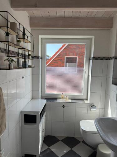 ein Badezimmer mit Fenster, Toilette und Waschbecken in der Unterkunft Hüs Sanskiin in Wittdün