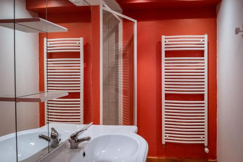 a bathroom with orange walls and a sink and a mirror at la margeride in Le Malzieu Forain
