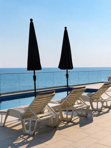 a group of chairs and umbrellas next to a swimming pool at Villa La Reina in Bar