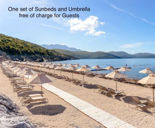 a group of umbrellas and chairs on a beach at Lux Studio Lustica Bay and Car in Luštica