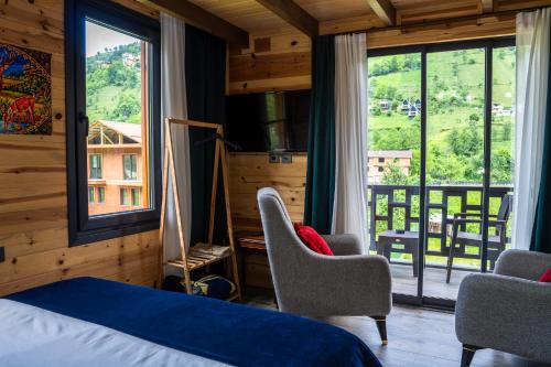 a bedroom with a bed and chairs and a large window at Pallas Suit in Ardeşen