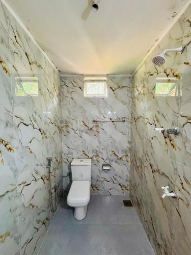 a bathroom with a toilet and a stone wall at Tropical Point Inn in Matara