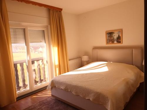 a bedroom with a bed and a large window at Guest House Mijić in Korenica