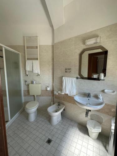 a bathroom with a sink and a toilet and a mirror at Hotel Trocadero - Koolibry Hotels in Cervia