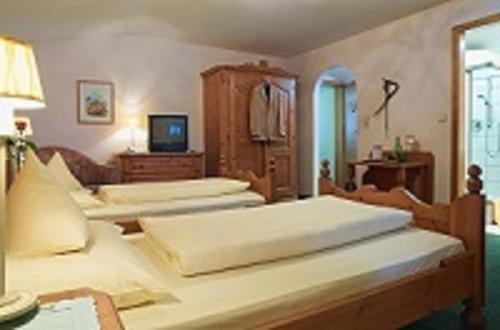 a bedroom with three beds and a tv in it at Hotel B&B "Zur Schanz" in Ebbs