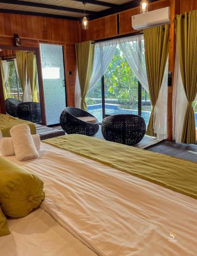 a large bed in a room with chairs at Private Pool Sun Shade Resort & Spa in Habarana