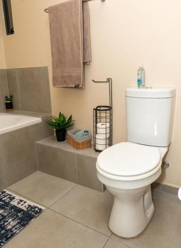 a bathroom with a white toilet and a bath tub at Modern 2 bedroom at Waterfall Ridge-Midrand in Midrand
