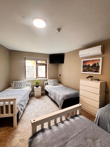 a bedroom with three beds and a tv in it at The Ambassador Apartment in Carrick on Shannon