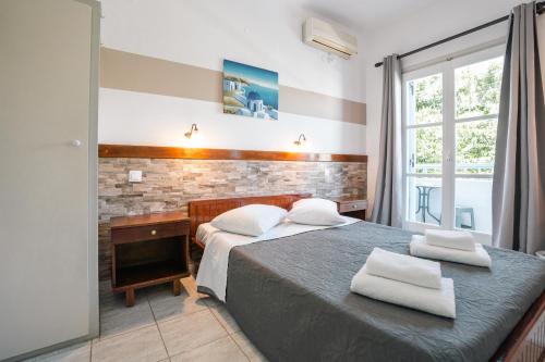 a bedroom with two beds and a desk and a window at Narkissos Hotel in Kamari