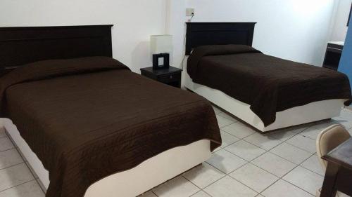 two beds sitting next to each other in a bedroom at Hotel Marina Topolobampo in Topolobampo