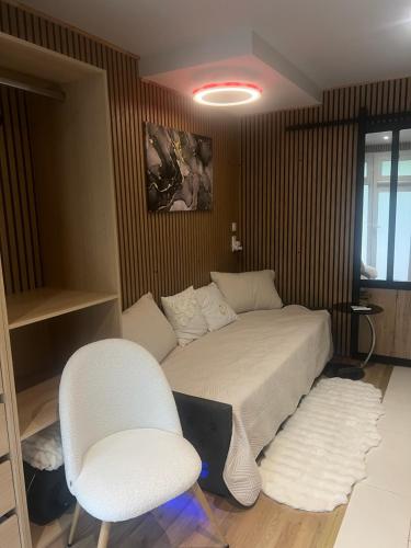 a bedroom with a bed and two white chairs at Studio meublé in Orsay