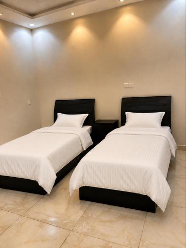 two beds sitting next to each other in a room at البساتين هومز - Al Basateen Homes in Al Baha