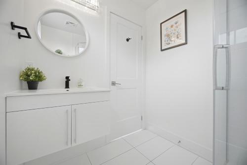 a white bathroom with a sink and a mirror at Exquisite, Bright & Modern Condo - Free Parking in Niagara Falls