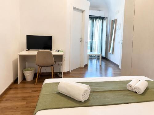 a bedroom with a bed and a desk with a television at Zurria Rooms in Catania