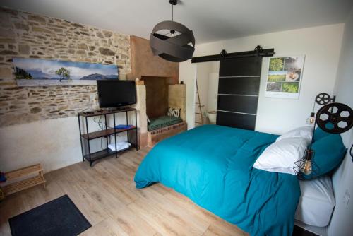 a bedroom with a blue bed and a tv at Ferme du ru paisible in Tournières