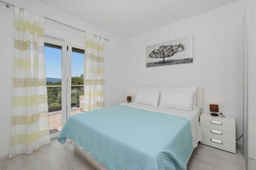 a white bedroom with a bed and a window at House Green in Vrh