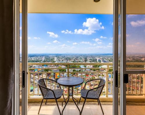 Ein Tisch und Stühle auf einem Balkon mit Aussicht in der Unterkunft Family-Ready Skyline Retreat near BGC with Free Parking in Manila