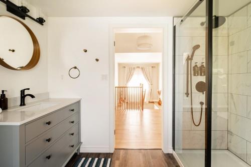 a bathroom with a shower and a sink and a mirror at Modern & Spacious 1908 Home in Stratford