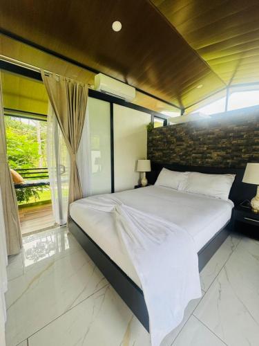a large white bed in a room with a window at Cabañas La Hermosa #2 in Guápiles