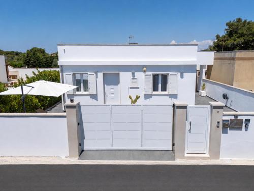 a white house with white doors and an umbrella at Lu Chiapparu B&B in Nardò