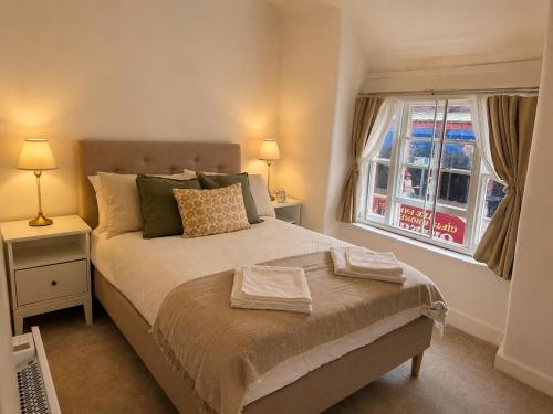 a bedroom with a bed with two lamps and a window at Historic High St Flat with Peaceful Garden Retreat in Stony Stratford