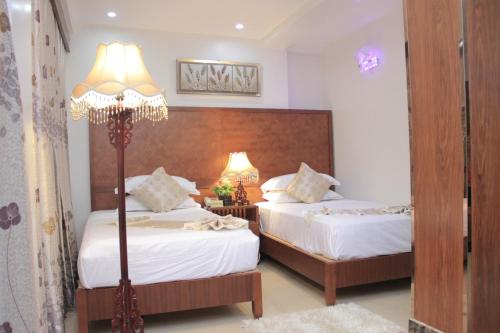 a bedroom with two beds and a lamp at Zimbo Golden Hotel in Dar es Salaam