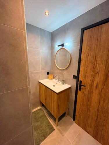 a bathroom with a sink and a mirror and a door at Villa du Parc le Lilas in Formiguères