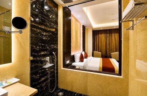 a bathroom with a bed and a shower with a mirror at Hotel Paarth in Ludhiana