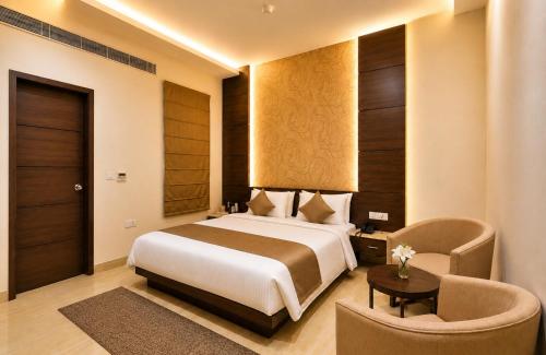 a hotel room with a bed and a chair at Hotel Paarth in Ludhiana