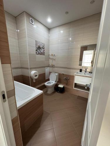 a bathroom with a tub and a toilet and a sink at Уютные комнаты-студии in Astana